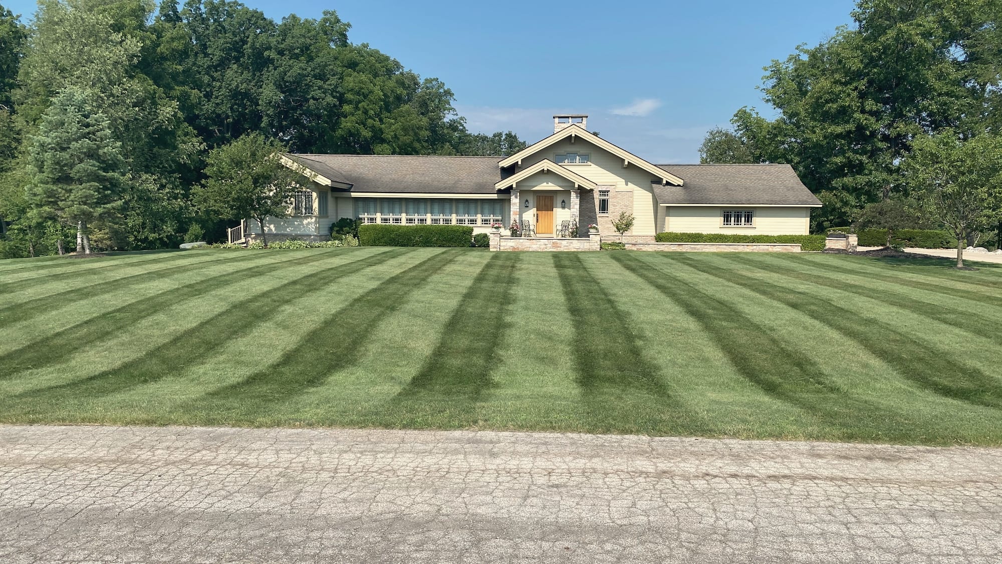 A wide front lawn mowed in even stripes in front of a ranch-style house